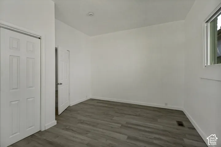 Wood-finish flooring with white baseboards, white walls, and a white ceiling