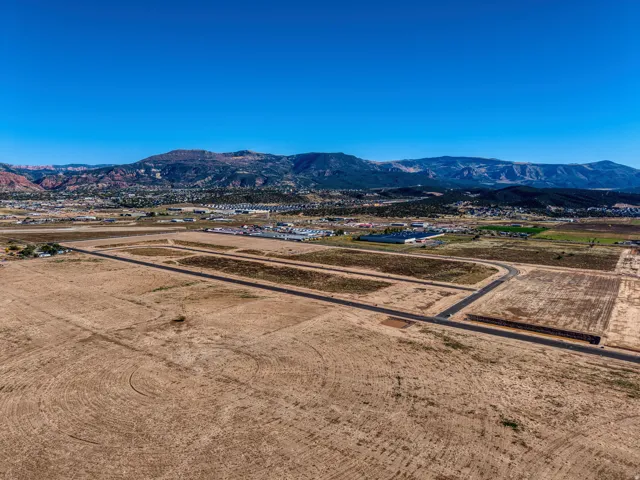 Expansive land parcel featuring new asphalt roadways, cleared development plots, and a mountainous backdrop