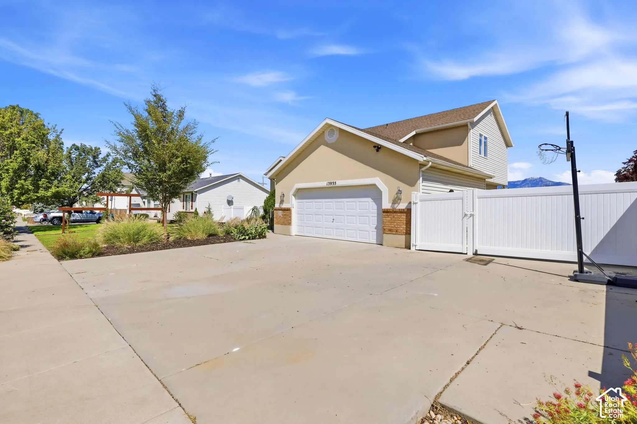 Driveway with a two-car garage, stucco and brick exterior, and a white privacy fence