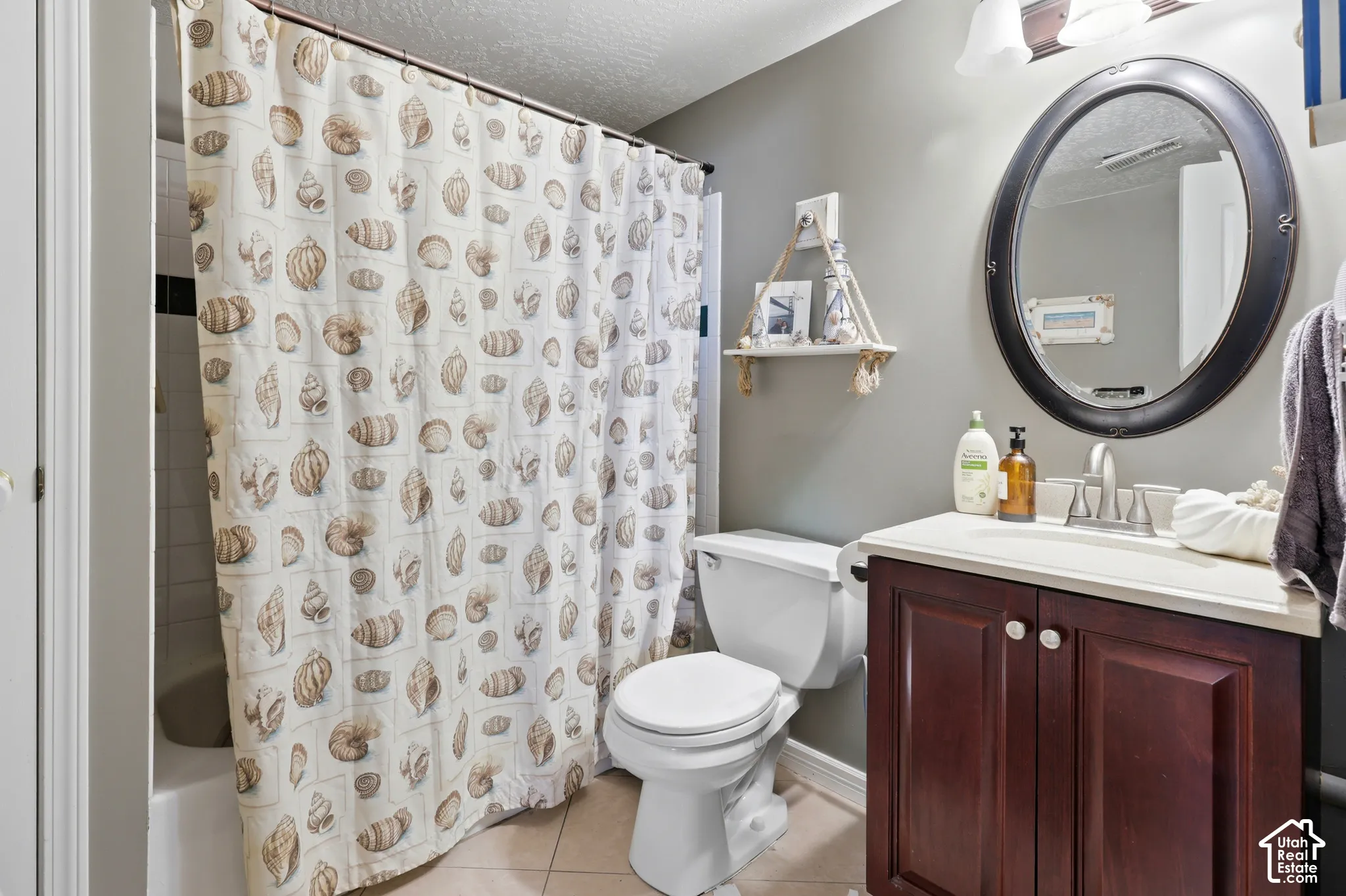 Bathroom featuring a single vanity with wood-finish cabinetry, a white countertop, and an oval mirror