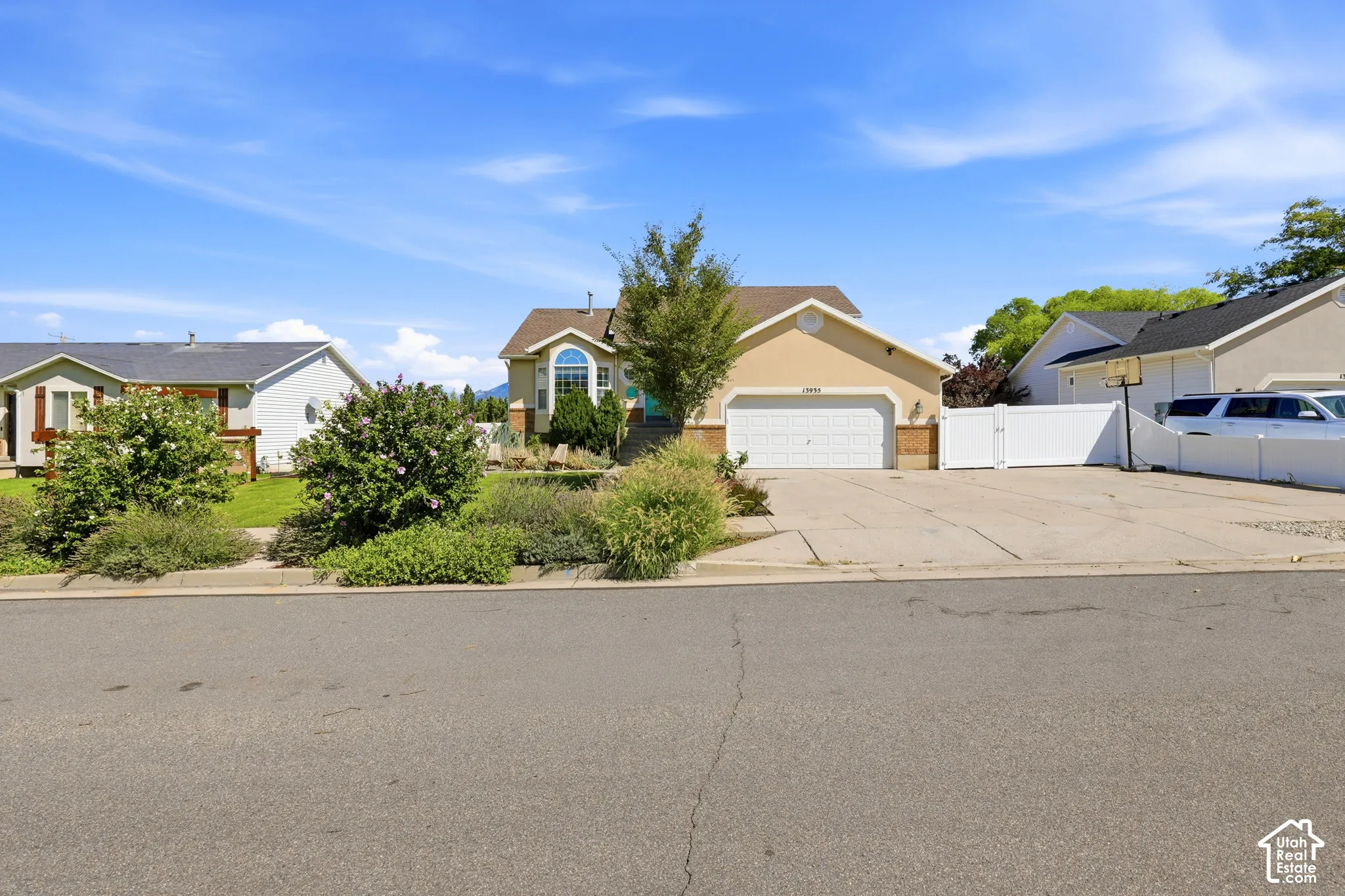 Single-story residence featuring an attached garage, arched window, and a white fence