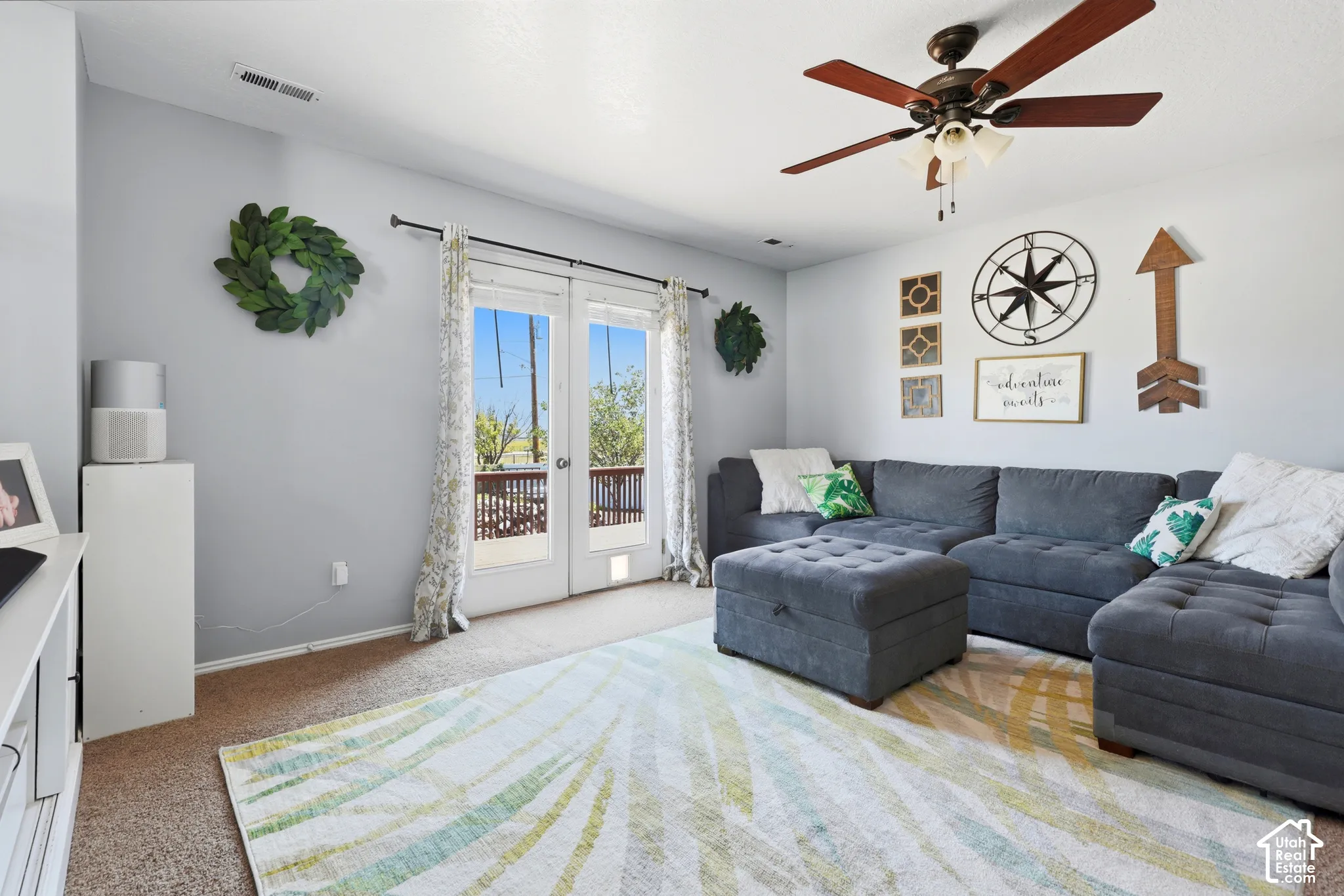 Spacious living area featuring neutral carpeting and a ceiling fan with integrated lighting