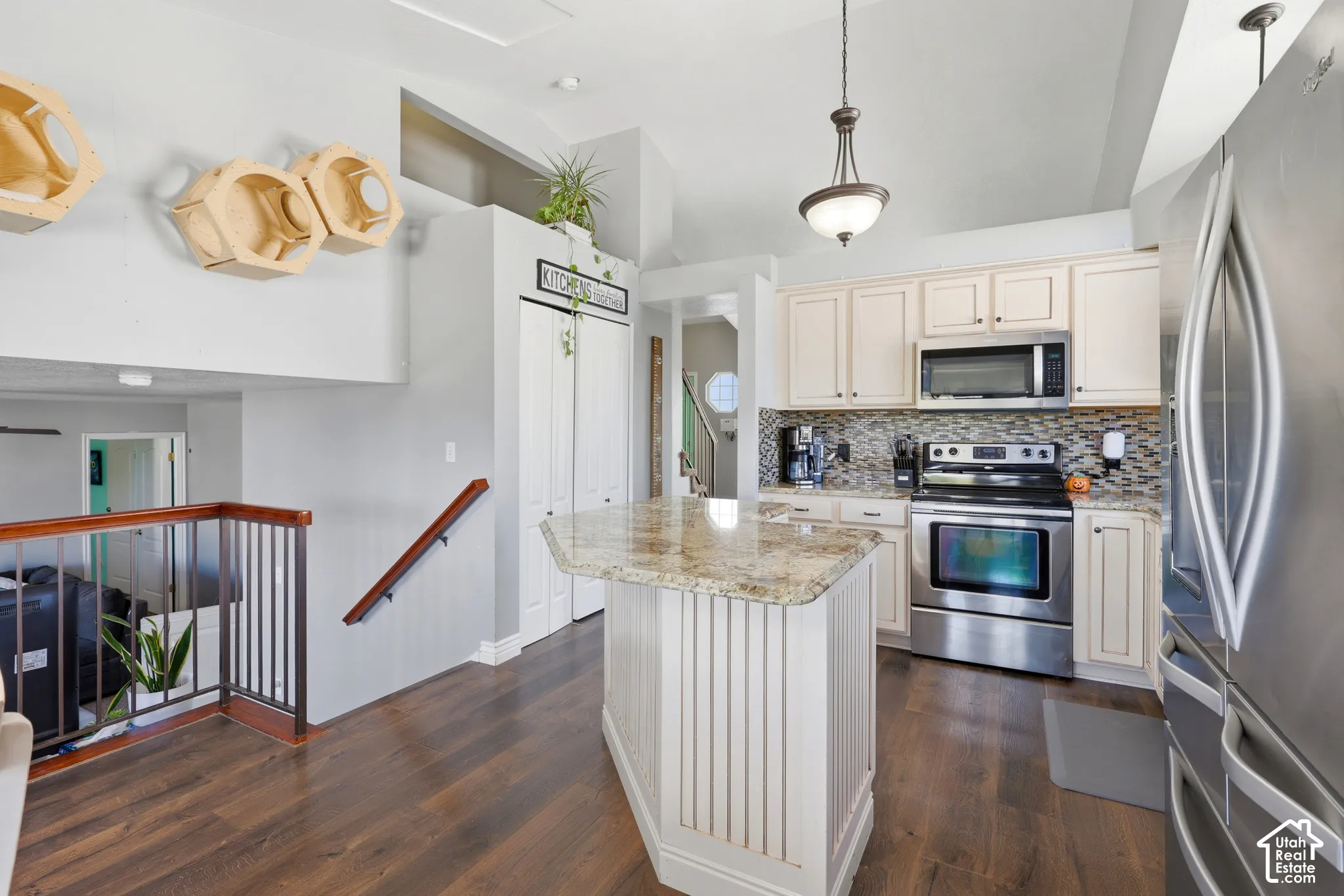 Kitchen featuring a granite-topped island, stainless steel appliances, wood-finish flooring, and white cabinetry