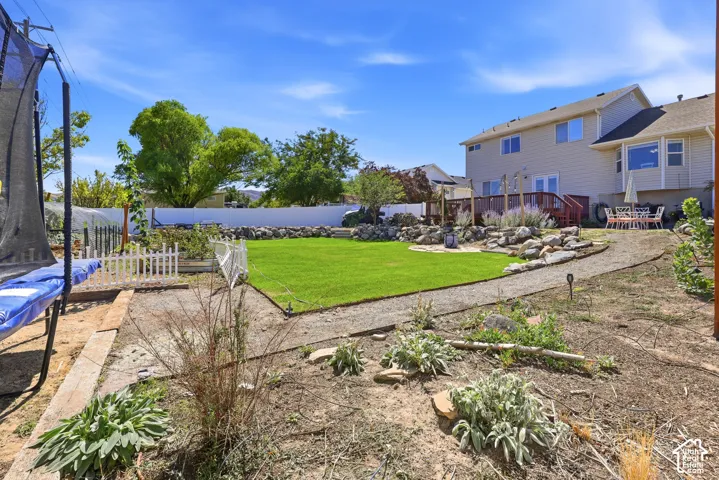 Expansive backyard with a manicured lawn, gravel pathways, and a white picket fence