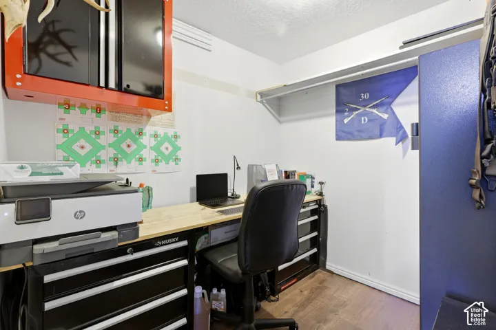 Built-in wood-finish desktop with integrated storage, wall-mounted red cabinetry, and wood-finish flooring