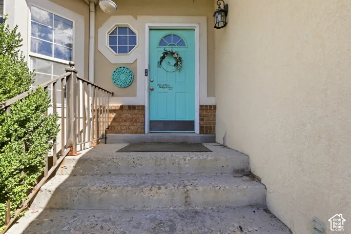 Stucco exterior with a vibrant turquoise entry door, complemented by a decorative octagonal window and a side window