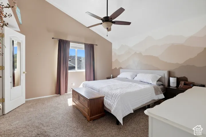 Vaulted ceiling with a ceiling fan, accent wall with a painted mural, and a window with a dark curtain