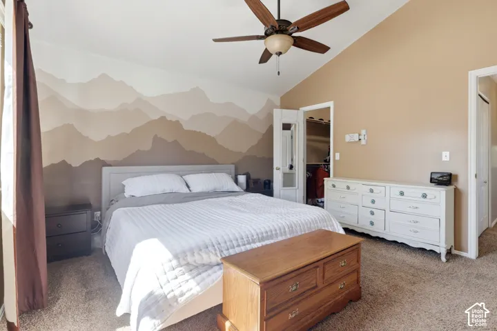 Vaulted ceiling with a ceiling fan, carpeted flooring, and a wall mural