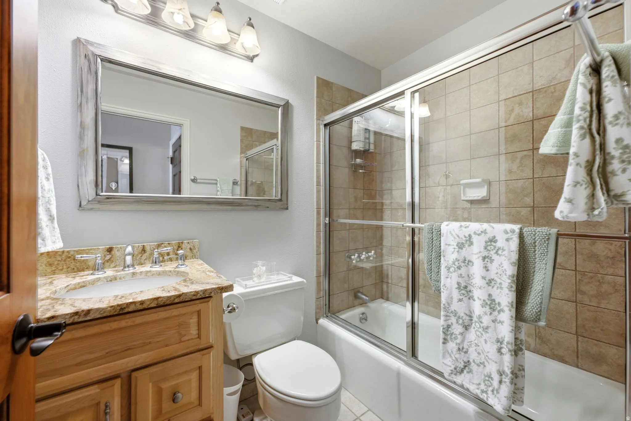 Vanity with a polished stone countertop, undermount sink, and wood-finish cabinetry