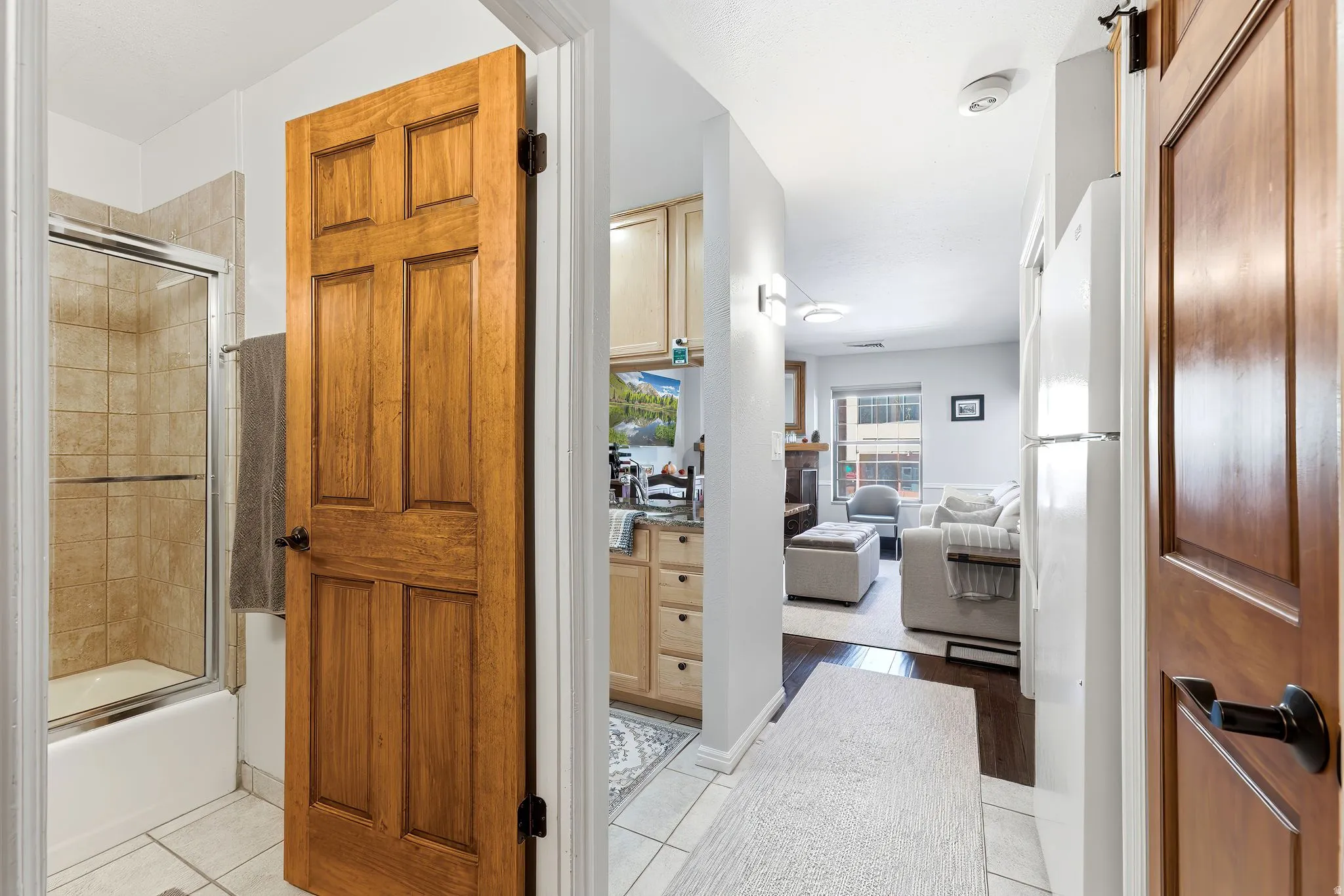Tiled bathroom flooring with a shower-over-tub combination, wood panel doors, recessed lighting, and wood-finish flooring