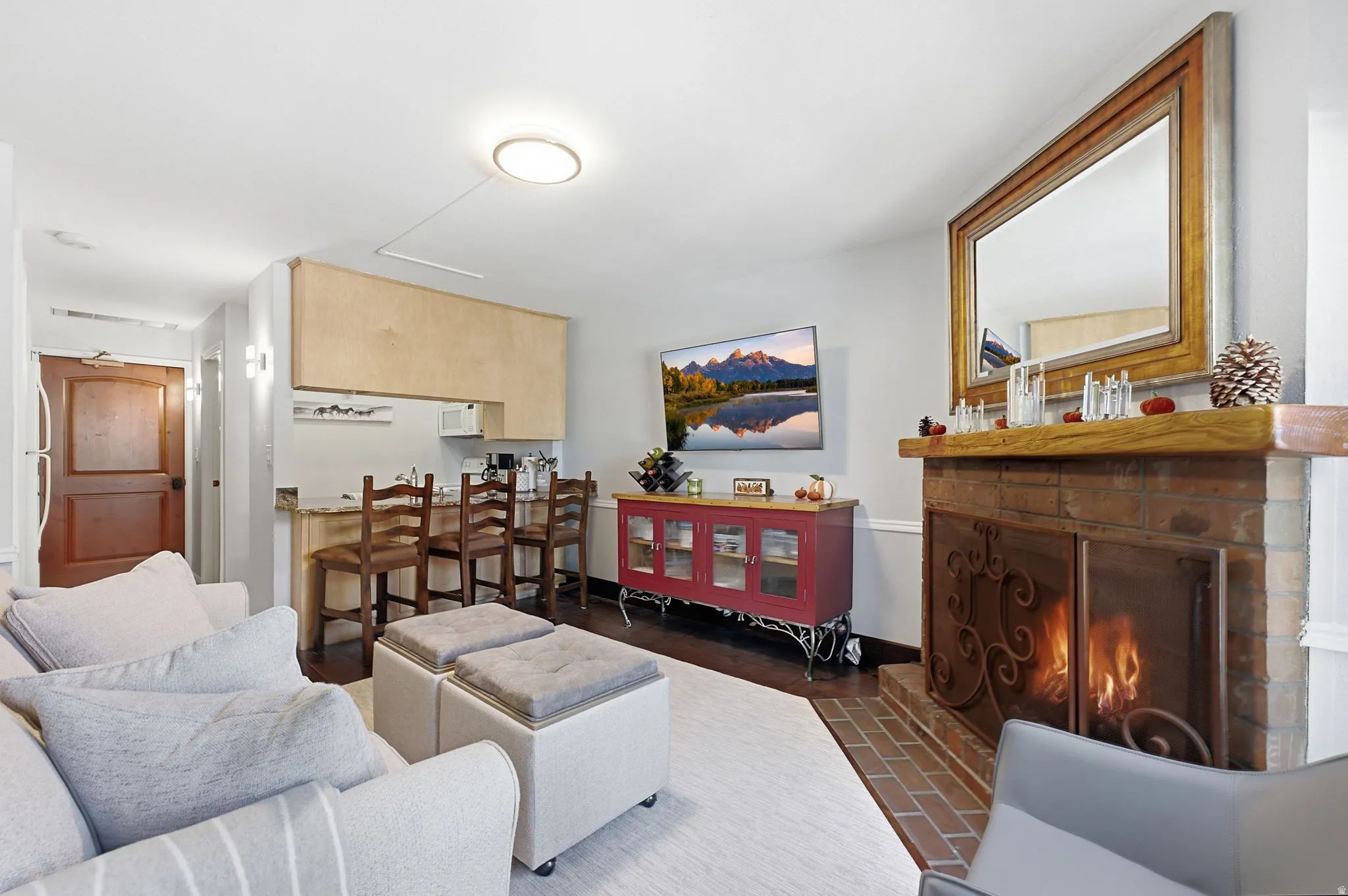 Brick fireplace with a wooden mantel, integrated fire screen, and dark wood-finish flooring