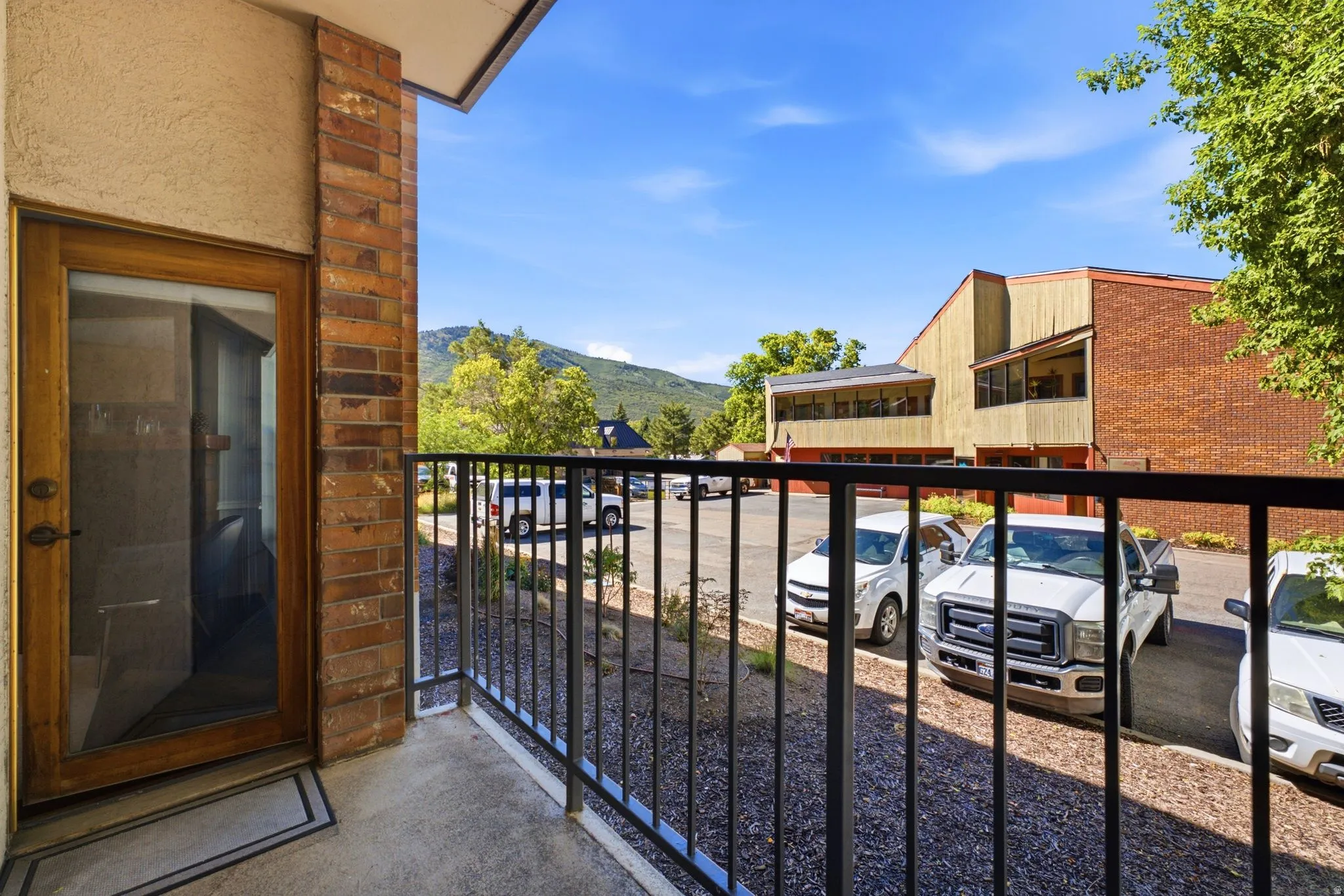 Balcony featuring a glass-paneled door, brick column, and black metal railing