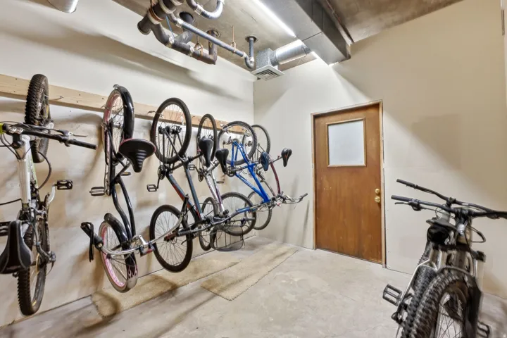 Concrete flooring, wood door with frosted glass panel, exposed ceiling ducts, wall-mounted storage racks