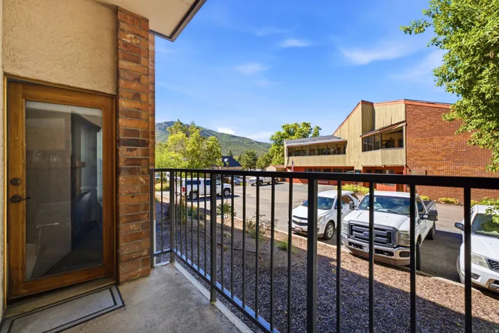Balcony featuring a glass-paneled door, brick column, and black metal railing
