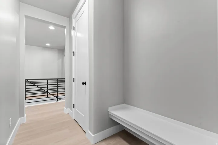 Built-in bench with storage, wood-finish flooring, recessed lighting, and metal railing