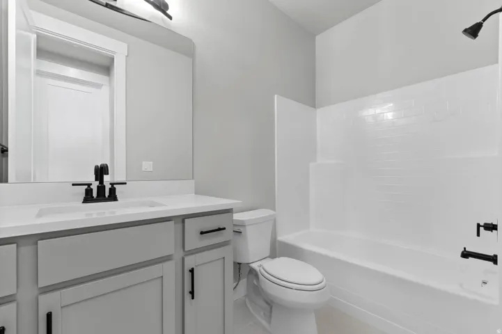 Bathroom featuring a light gray vanity with black hardware, white countertop, and a white integrated sink with a matte black faucet