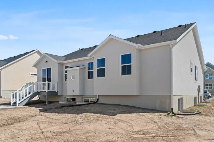 Rear exterior featuring a deck with white railings, a sliding glass door, multiple windows, and a shingle roof