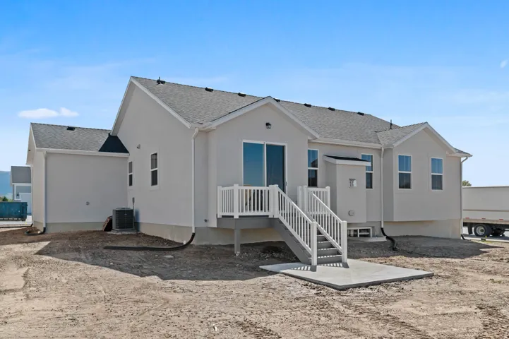 Exterior featuring light-toned stucco siding, a grey shingle roof, and a rear deck with white railings