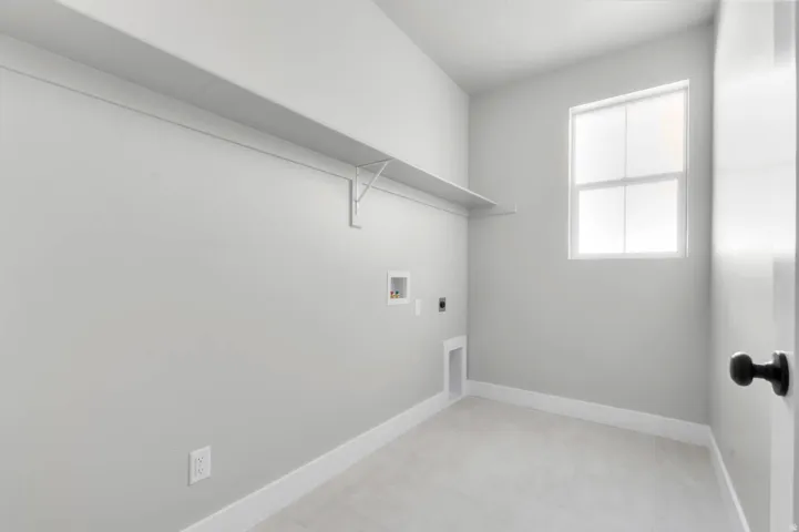 Windowed utility room with a white wall shelf, tile flooring, and white trim