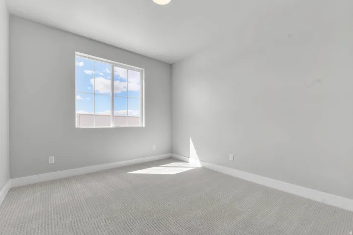 Windowed room featuring light gray walls, white trim, and a patterned carpet