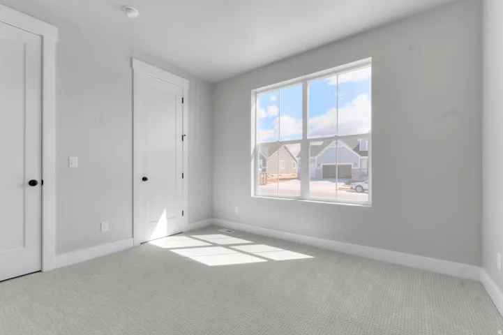 Bright room featuring carpeted flooring, white trim, and a large multi-pane window