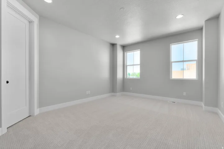Recessed lighting, light-toned carpeting, two windows, painted walls, and a white interior door