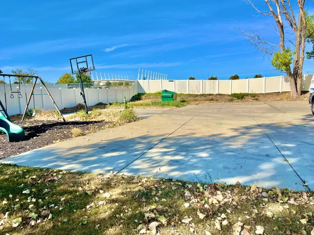 Expansive concrete slab, bordered by a white privacy fence