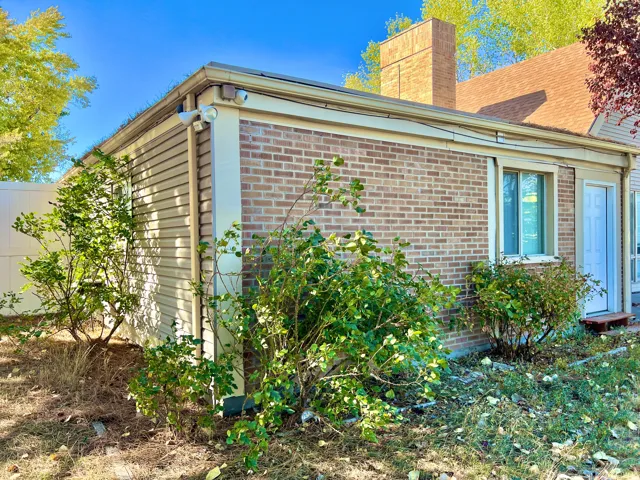 Exterior featuring brick and siding finishes, a shingle roof, a prominent brick chimney, and a white entry door
