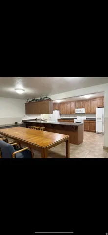 Kitchen featuring wood cabinetry, white appliances, and a central island