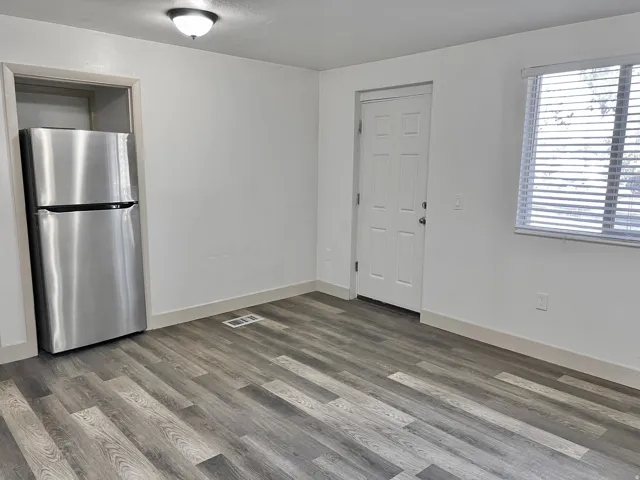 Wood-finish flooring, white walls, and a stainless steel refrigerator