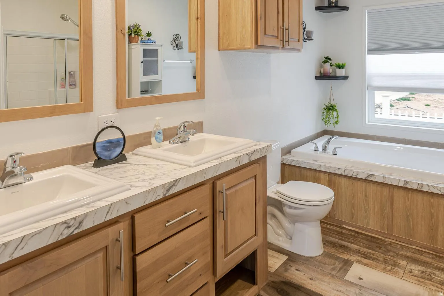 Dual vanity with integrated sinks, wood-finish cabinetry, and a patterned countertop