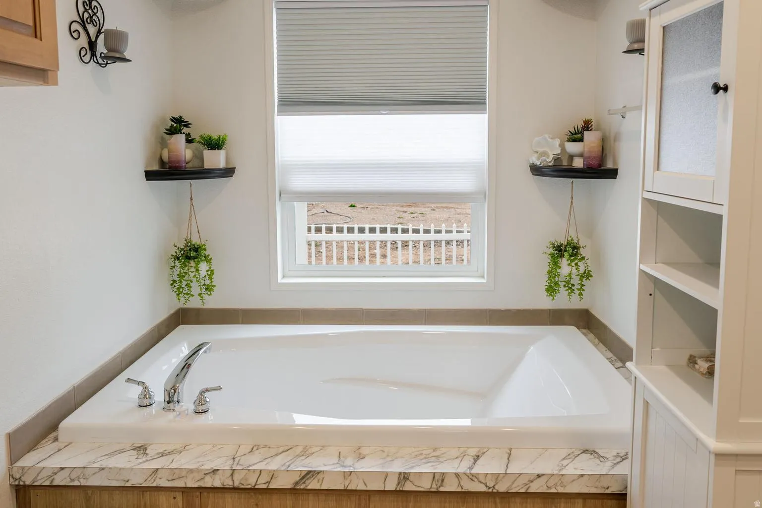 Built-in soaking tub with chrome fixtures, wood-finish paneling, and a stone-finish countertop