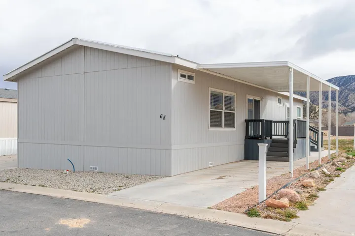 Light grey siding with white trim, covered patio, dark grey porch, gravel landscaping, paved parking