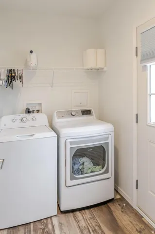 Laundry area featuring wood-finish flooring, white walls, and a white wired shelf