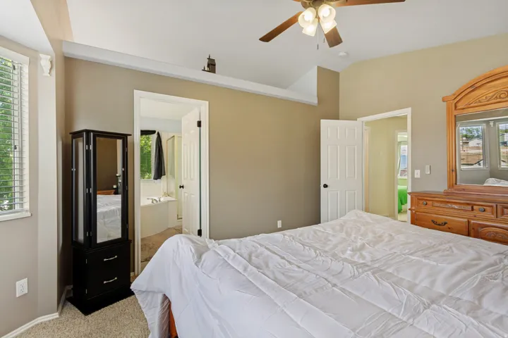 Vaulted ceiling with a ceiling fan, carpeted flooring, and window with blinds