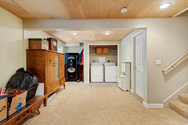 Carpeted flooring, recessed lighting, wood-finish ceiling, laundry area with appliances, and a wood handrail