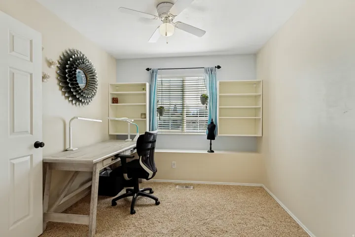Built-in shelving, window with blinds, ceiling fan, and carpeted flooring