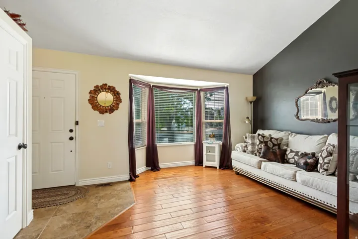 Wood-finish flooring, bay window, vaulted ceiling, two-tone wall, and a paneled entry door