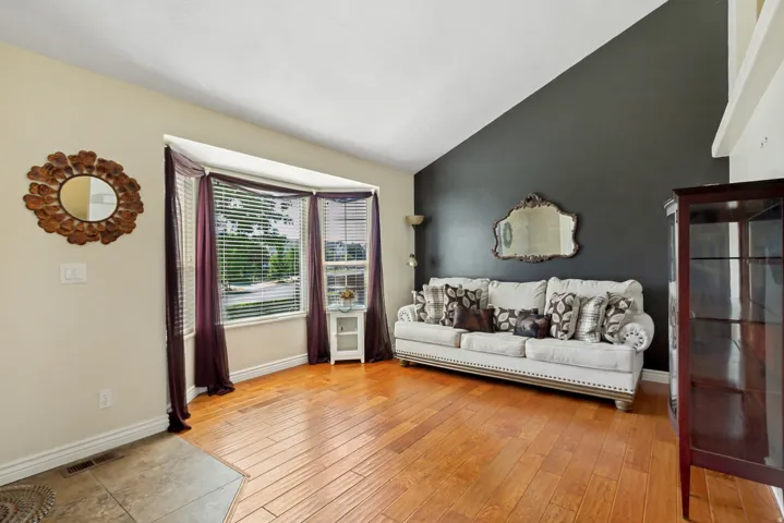 Vaulted ceiling, bay window, wood-finish flooring, two-tone wall treatment, built-in shelving unit