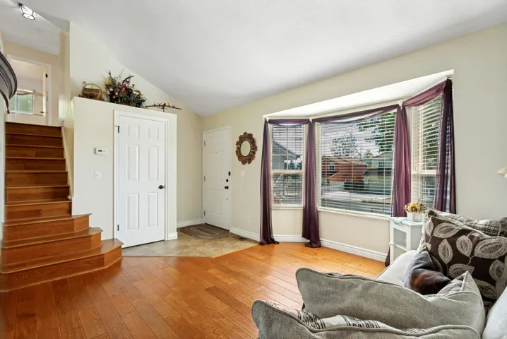 Hardwood flooring, natural light from a bay window, and a built-in staircase
