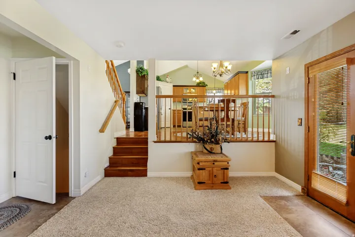 Split-level interior with wood-finish stairs, light-colored carpeting, a kitchen featuring wood cabinetry, and a glass-paneled entry door