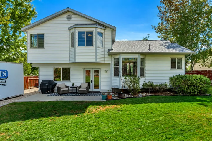 Expansive lawn area with a concrete patio, white siding, and a bay window