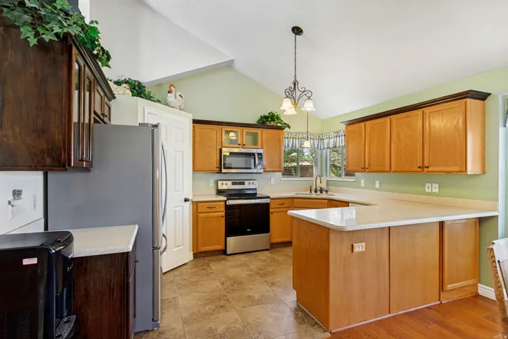 Kitchen featuring light wood cabinetry, white countertops, tile flooring, and vaulted ceilings