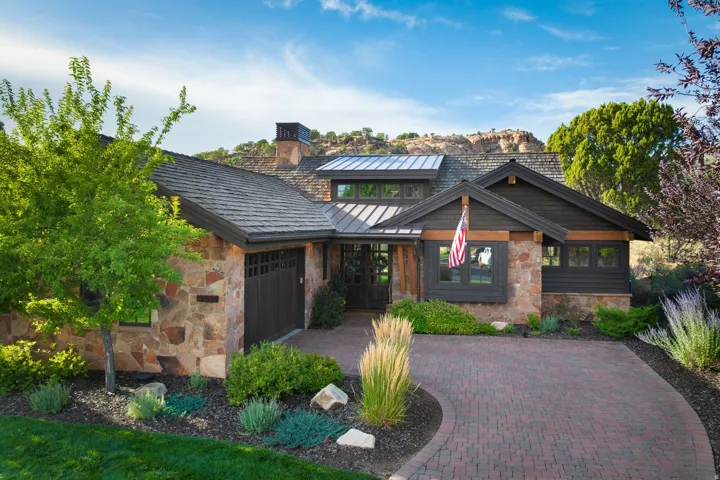 Stone and wood exterior with a brick paver driveway
