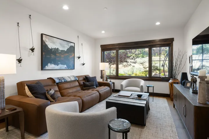 Recessed lighting illuminates this bright interior space, featuring wood-framed windows and wood-finish flooring