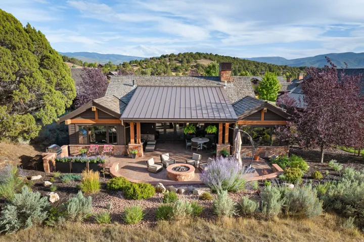 Expansive patio featuring a built-in fire pit, covered outdoor living space, and a mix of paved and landscaped areas