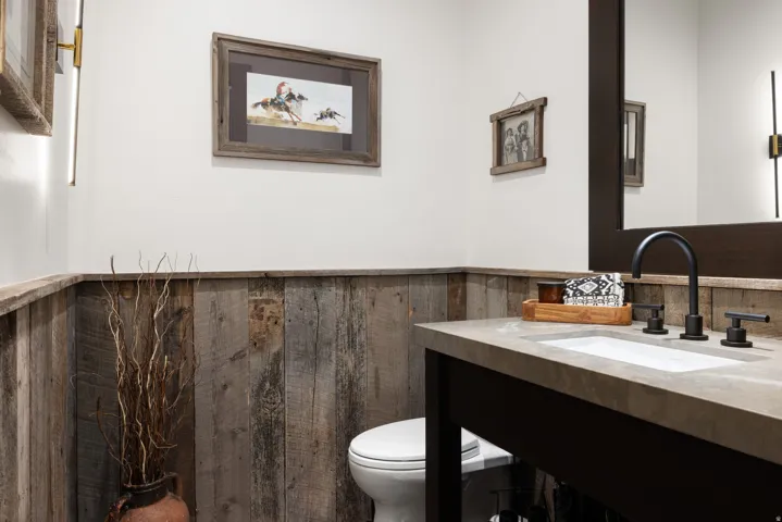 Shiplap wainscoting, solid surface countertop, integrated sink, matte black faucet, and a wall-mounted mirror