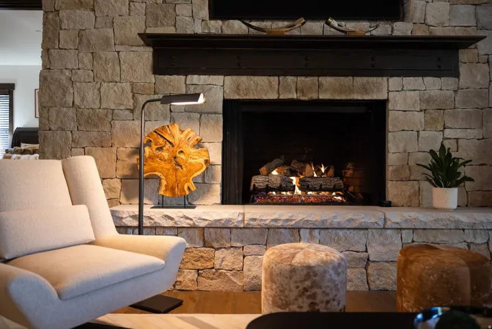 Stone-clad fireplace with a dark wood mantel and a gas insert