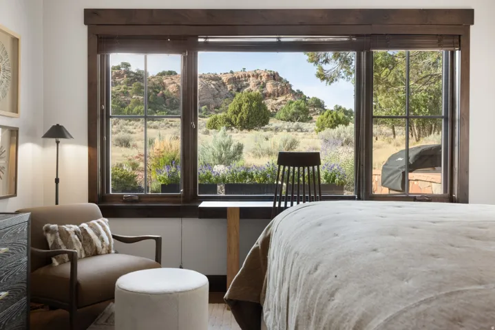 Expansive picture window with dark wood trim, offering a backdrop of natural rock formations and abundant vegetation