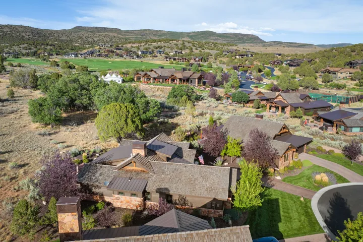 Expansive property with a shingle roof and metal roof accents, featuring a stone chimney and mature landscaping